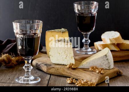 Un plateau de fromages avec du pain, des noix et du vin rouge Banque D'Images