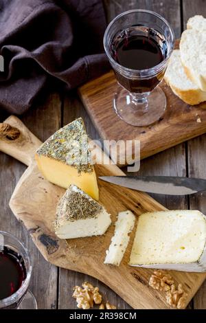 Un plateau de fromages avec du pain, des noix et du vin rouge Banque D'Images