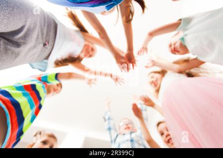 Groupe d'enfants mettent leurs mains vers le haut, arrière-plan flou Banque D'Images