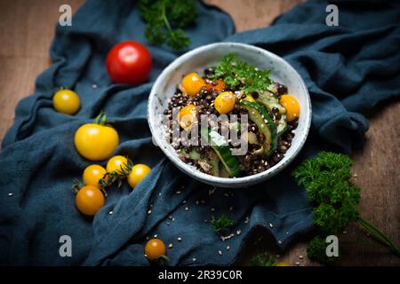 Salade de lentilles végétaliennes chaudes avec concombres, tomates, oignons et graines de sésame Banque D'Images