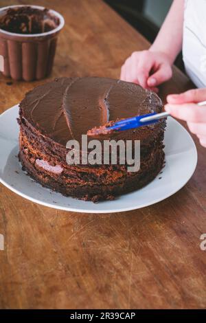 Un enfant fait du gâteau au chocolat à une table en bois Banque D'Images