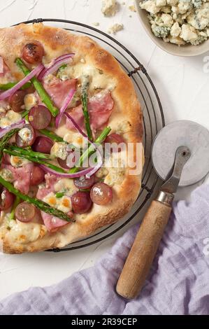 Pizza avec jambon, raisins, asperges et fromage bleu Banque D'Images