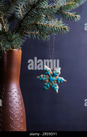 Biscuits de Noël végétaliens avec glaçage suspendus sur une branche de pin Banque D'Images