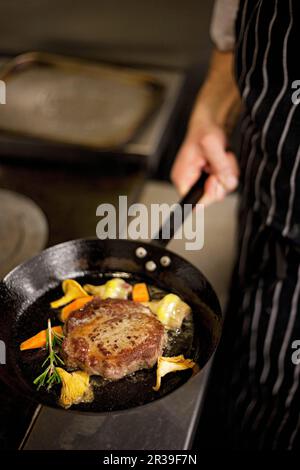 Steak aux yeux de côtes avec chanterelle et légumes dans une casserole tenue par un chef Banque D'Images