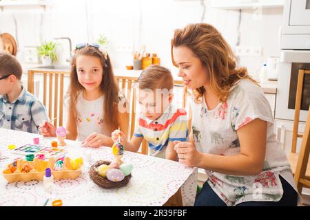 La mère et les enfants peignent et décorent des œufs colorés Banque D'Images