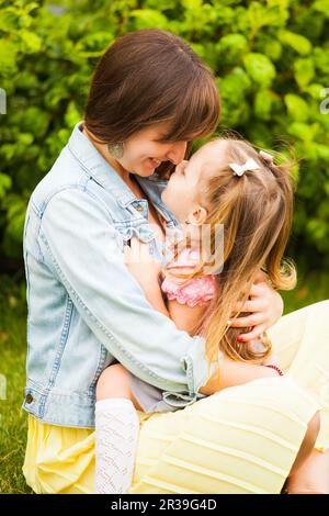 Bonne mère et fille embrassant et embrassant dans le parc d'été. Banque D'Images