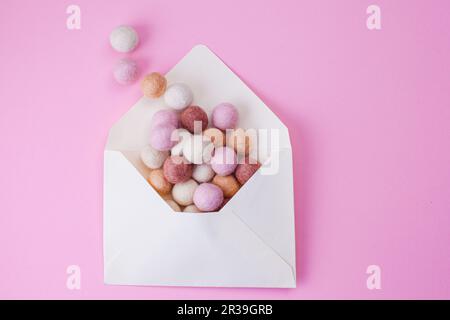 Des boules de feutre faites main colorées sortent de l'enveloppe en papier. Concept de message, de courrier et de lettre Banque D'Images