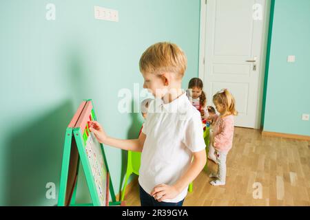 Adorable garçon étudiant les lettres et les chiffres à la carte magnétique Banque D'Images