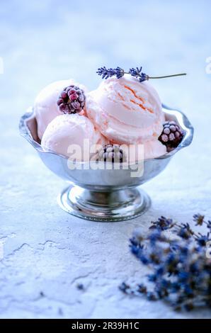 Boules de crème glacée roses dans des bols de crème glacée aux mûres et à la lavande Banque D'Images