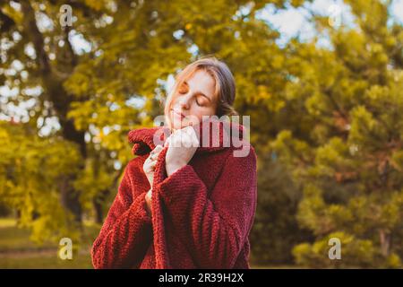 Femme se enveloppant dans un élégant manteau d'automne Banque D'Images