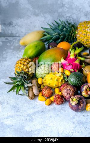 Une grande pile de fruits tropicaux frais et savoureux sur fond gris Banque D'Images