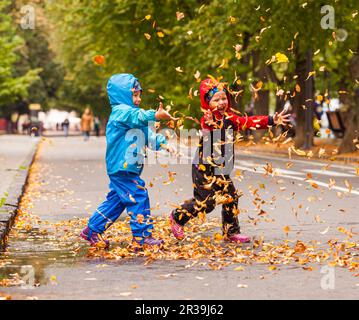 Les enfants s'amusent à jouer avec des feuilles tombées Banque D'Images