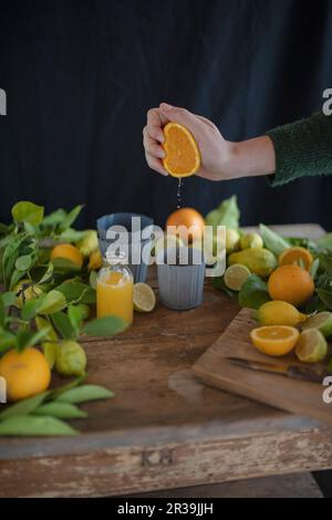 Jus d'orange fraîchement pressé et agrumes frais sur une table rustique en bois Banque D'Images