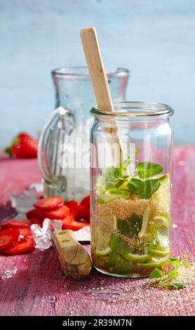 Punch sans alcool avec fraises, limes, menthe et cassonade en cours de fabrication Banque D'Images