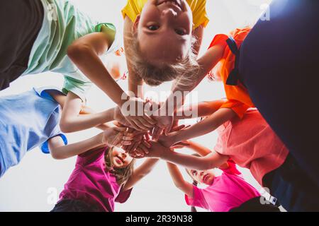 Les enfants heureux qui mettent leurs mains ensemble à l'extérieur. Jeux et loisirs d'été en plein air. Banque D'Images