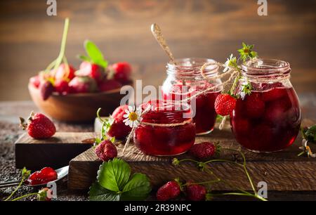 Confiture de fraises maison dans des pots en verre sur bois dans un style rustique. Nourriture saine pour le petit déjeuner Banque D'Images