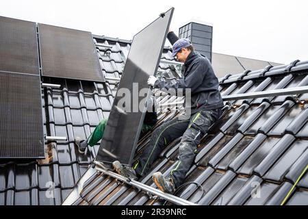 Équipe de techniciens installant des panneaux solaires sur le toit d'une maison Banque D'Images