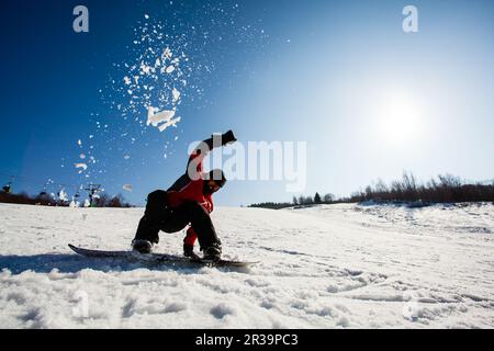 Homme sur un snowboard tombant sur la neige Banque D'Images