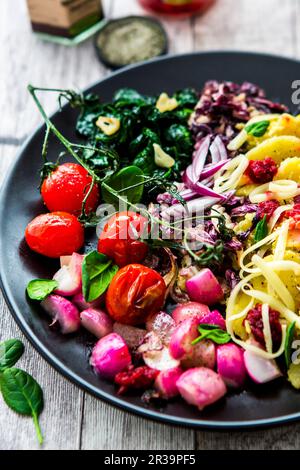 Un bol de petit déjeuner avec pommes de terre, épinards, tomates, radis et fromage Banque D'Images