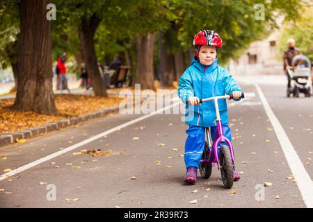Petit garçon en vêtements bleus d'automne sur son vélo Banque D'Images