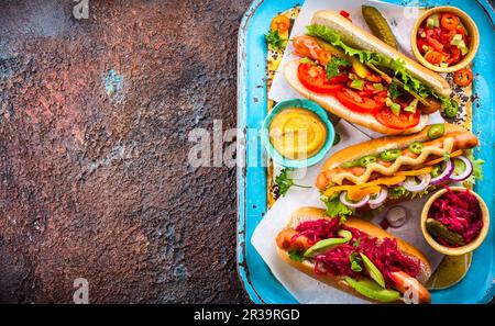 Variété de délicieux hot dogs avec légumes et sauces sur un plateau de service vintage Vue de dessus. Banque D'Images