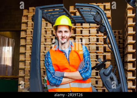 Un employé souriant qui conduit le chariot élévateur à fourche dans l'entrepôt. Concept de l'industrie du bois. Banque D'Images