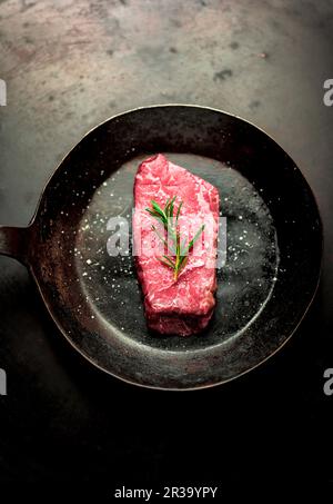 Un steak de bœuf au romarin dans une casserole Banque D'Images