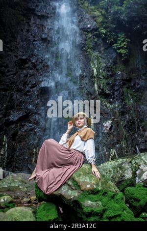 Une femme qui profite de la beauté naturelle de la chute d'eau Batu Hanoman, Tasikmalaya, West Java, Indonésie Banque D'Images