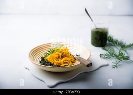 Spirales de carottes jaunes avec pesto vegan faites de feuilles de carottes Banque D'Images