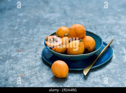 Fruits Medlar dans un bol bleu Banque D'Images