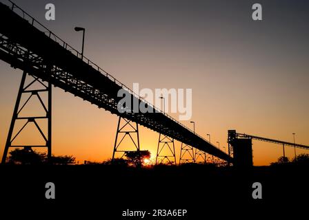 Silhouette de silo minier et de tapis transporteurs au coucher du soleil Banque D'Images