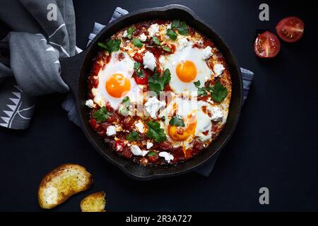 Shakshuka avec tomates, poivrons, oignons et œufs préparés dans une poêle en fonte Banque D'Images