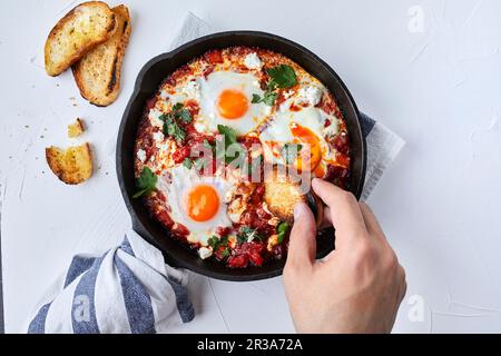 Shakshuka avec tomates, poivrons, oignons et œufs préparés dans une poêle en fonte Banque D'Images