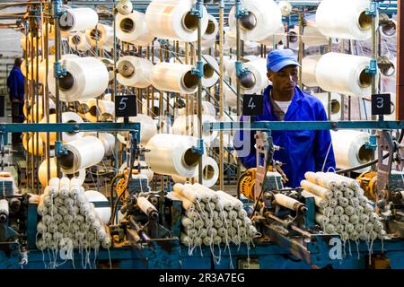 Travailleur d'usine africain sur un métier à tisser de ligne de montage de trame de cobobineuse Banque D'Images