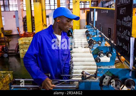 Travailleur d'usine africain sur un métier à tisser de ligne de montage de trame de cobobineuse Banque D'Images