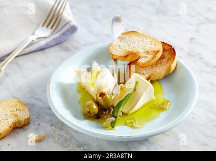 Camembert crémeux mariné aux olives, oignon et sauge servi avec de la baguette grillée Banque D'Images