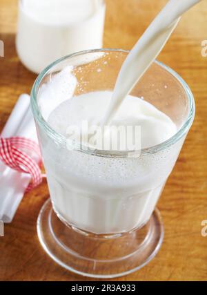 Du lait froid et frais est versé dans un verre Banque D'Images