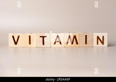Le mot VITAMINE sur des cubes en bois sur un fond beige neutre studio. Copier l'espace. Écrit. Les mots de texte ont leur importance. Suppléments pour la santé humaine. Essentiel Banque D'Images