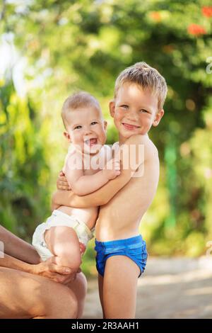 Petits enfants jouant à l'extérieur le jour d'été chaud. Un petit garçon tient les mains de sa petite sœur Banque D'Images