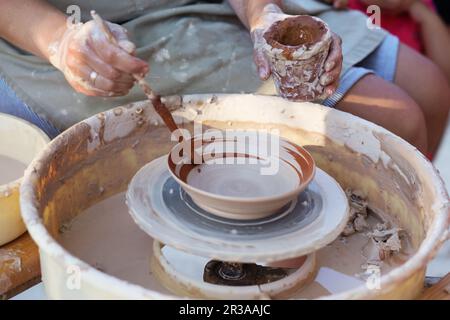 Mains de fille potter, créant un pot de terre sur le cercle, gros plan Banque D'Images