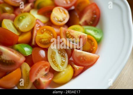 Tomates colorées, coupées en deux et coupées en quartiers, sur une assiette Banque D'Images