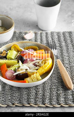 Saupoudrer de légumes mélangés avec du parmesan. Les légumes rôtis se mélangent sur l'assiette avec les couverts sur le t Banque D'Images