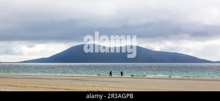 Deux marcheurs et deux chiens marchant sur les rives de LUSKENTIRE Beach, Harris, Isle of Harris, Outer Hebrides, Western Isles, Écosse, Royaume-Uni Banque D'Images