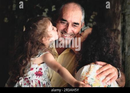 3 générations portrait de style de vie tourné - une femme et sa fille embrassant le père / grand-père - blanc famille caucasienne célébrant un moment heureux Banque D'Images