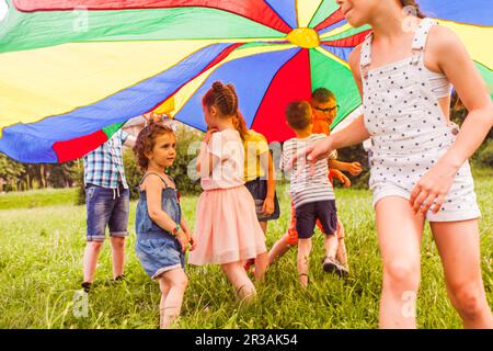 Petite fille essayant de rejoindre le jeu actif des enfants plus âgés Banque D'Images