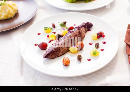 Morceau de viande de cerf rôti sur une assiette blanche Banque D'Images