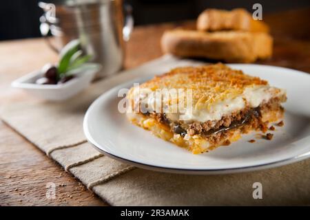 un morceau de mousaka grec servi sur une assiette et du pain sur le fond Banque D'Images