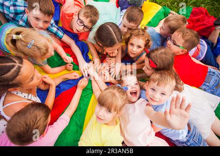 Enfants se posant ensemble en cercle sur un sol coloré Banque D'Images