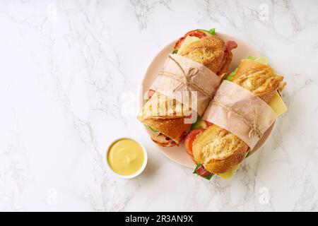 Grands sandwiches de baguette frais avec bacon, chedder, moutarde, laitue et légumes Banque D'Images