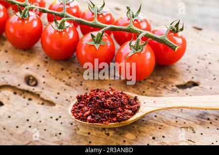 Cuillère en bois remplie de condiment de tomate séchée et moulu Banque D'Images